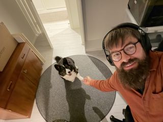 A black and white corgi cardigan and a bearded man photographed from above. They are giving each other the hand/paw.